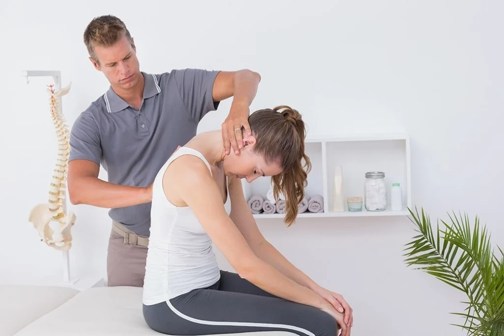 A woman getting treatment on her upper back and neck by a chiropractor.