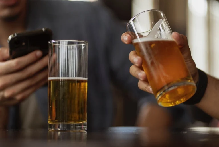 Two glasses of beer, one of them held by a man.