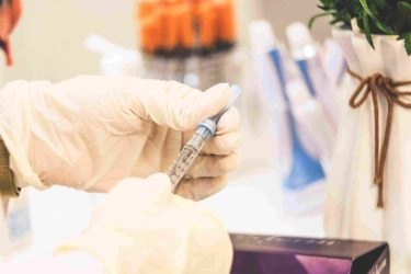 A syringe held by a person with latex gloves.