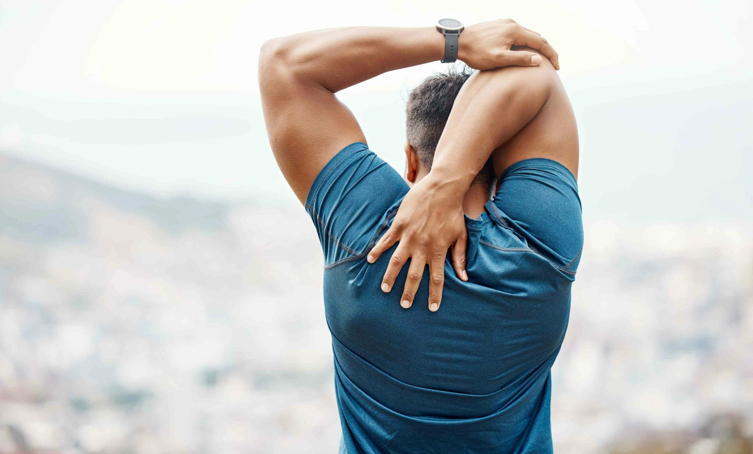 A fit man stretching his shoulder.