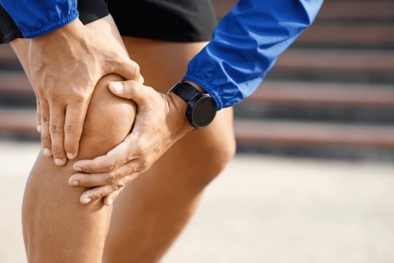 A man touching his knee with both hands.