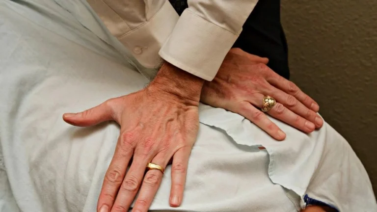 A chiropractor doing a reverse hand push to a patient's back.