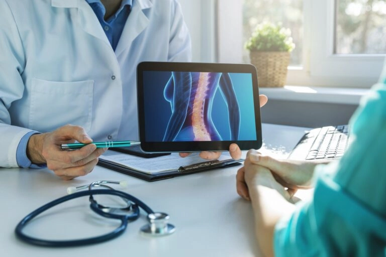 A doctor showing an x-ray image on his tablet to a patient.