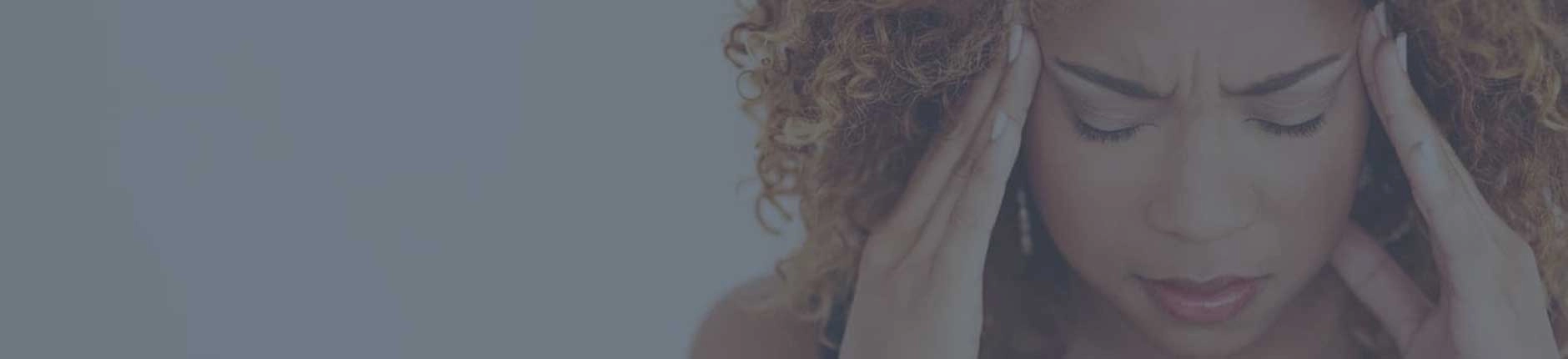 A woman touching the sides of her forehead in pain.