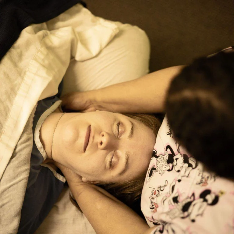 A woman having a neck massage by another person while lying on her back.