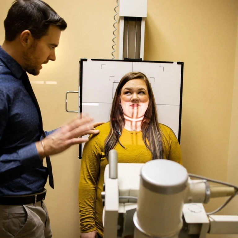 A patient with a doctor preparing in front of an activated x-ray scanner.