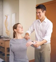 A man treating a woman in her shoulder.