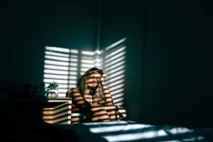 A woman sitting in the corner of a dark room.