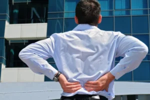 A man touching his lower back with both their hands.