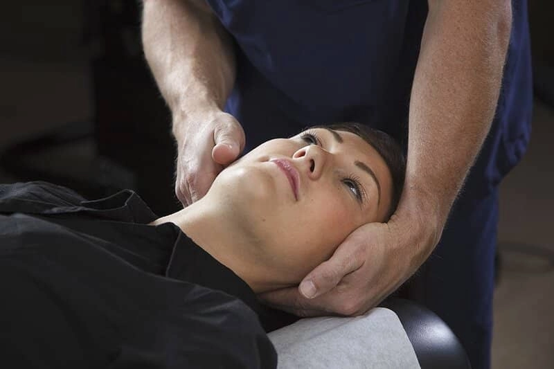 A woman being treated in her neck by a chiropractor.