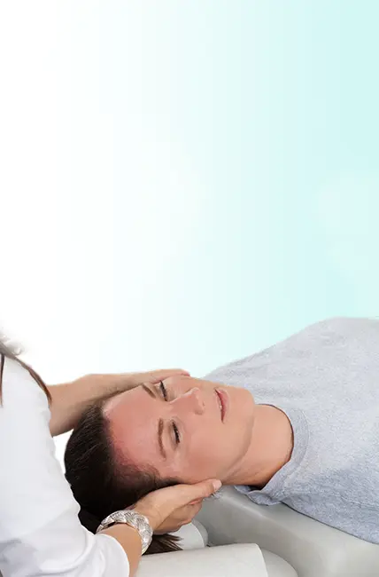 A woman lying on her back and getting treated in the neck by a chiropractor.