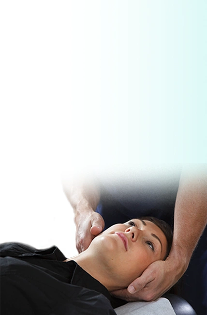 A female patient lying face up and getting treatment for whiplash by a chiropractor.