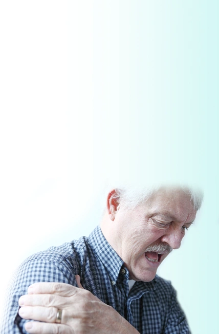 An elderly man touching his right shoulder in pain.