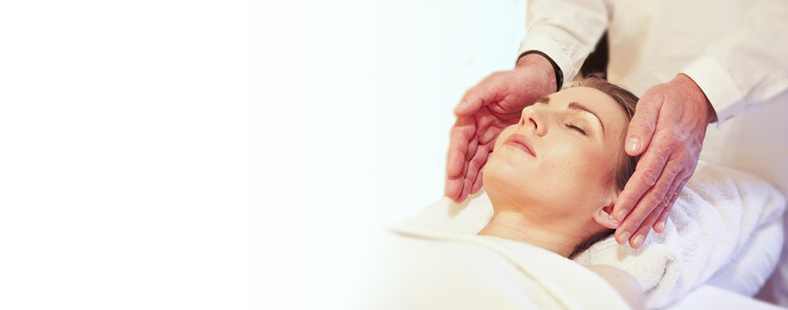 A patient lying on their back and a chiropractor having their hands on each side of the patient's head.