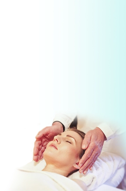 A patient lying on their back and a chiropractor having their hands on each side of the patient's head.