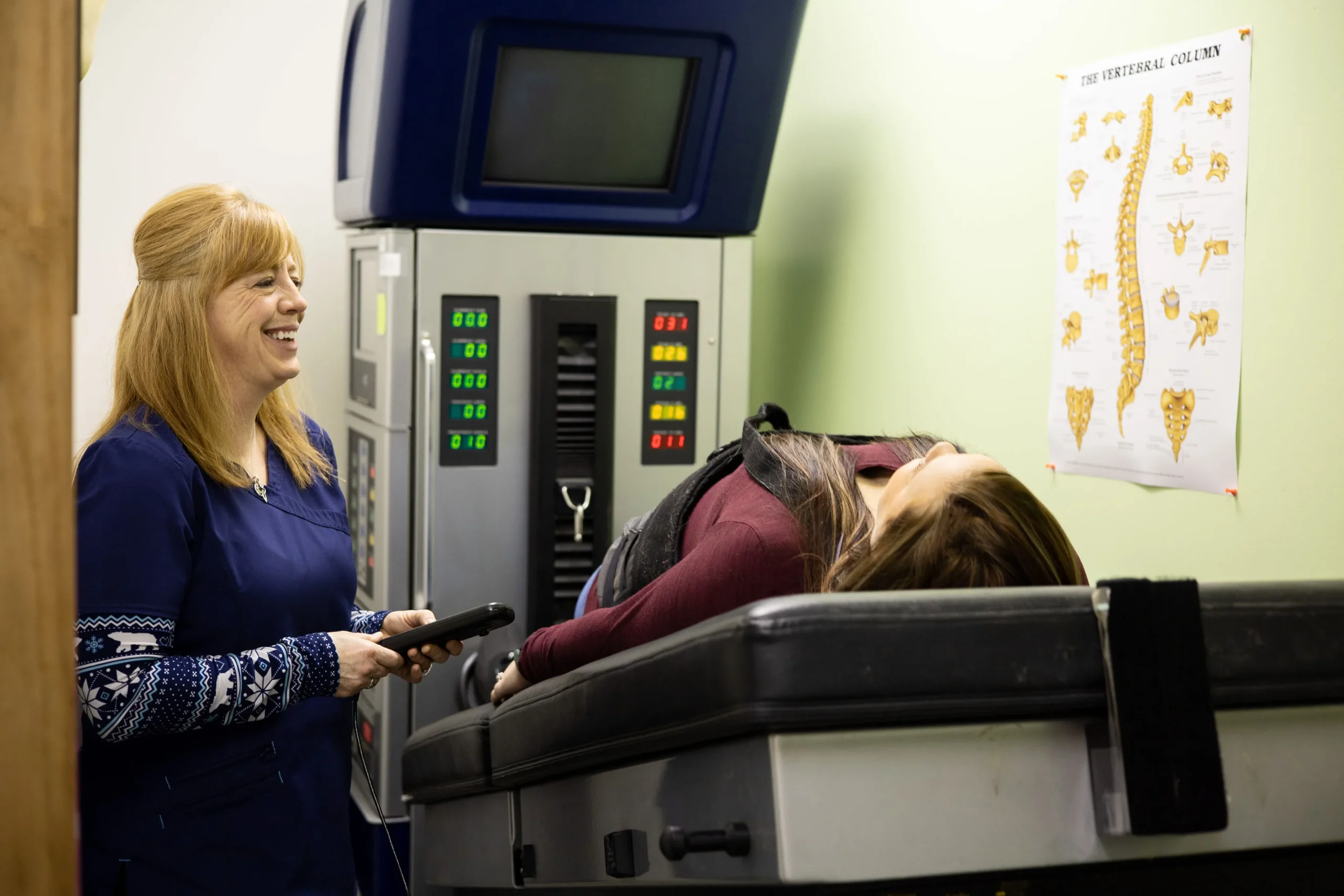 A member of Better Health Alaska chatting with a patient while facilitating the use of a DRS System machine for that patient.