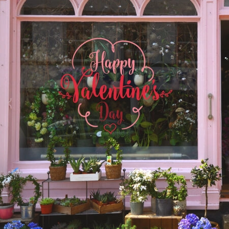 flower shop storefront with colorful flower on display. Pink, wh