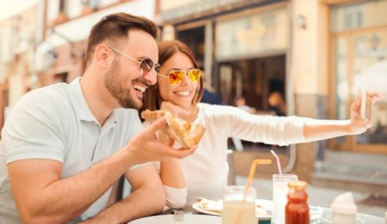 Όμορφο χαμογελαστό ζευγάρι απολαμβάνει πίτσα